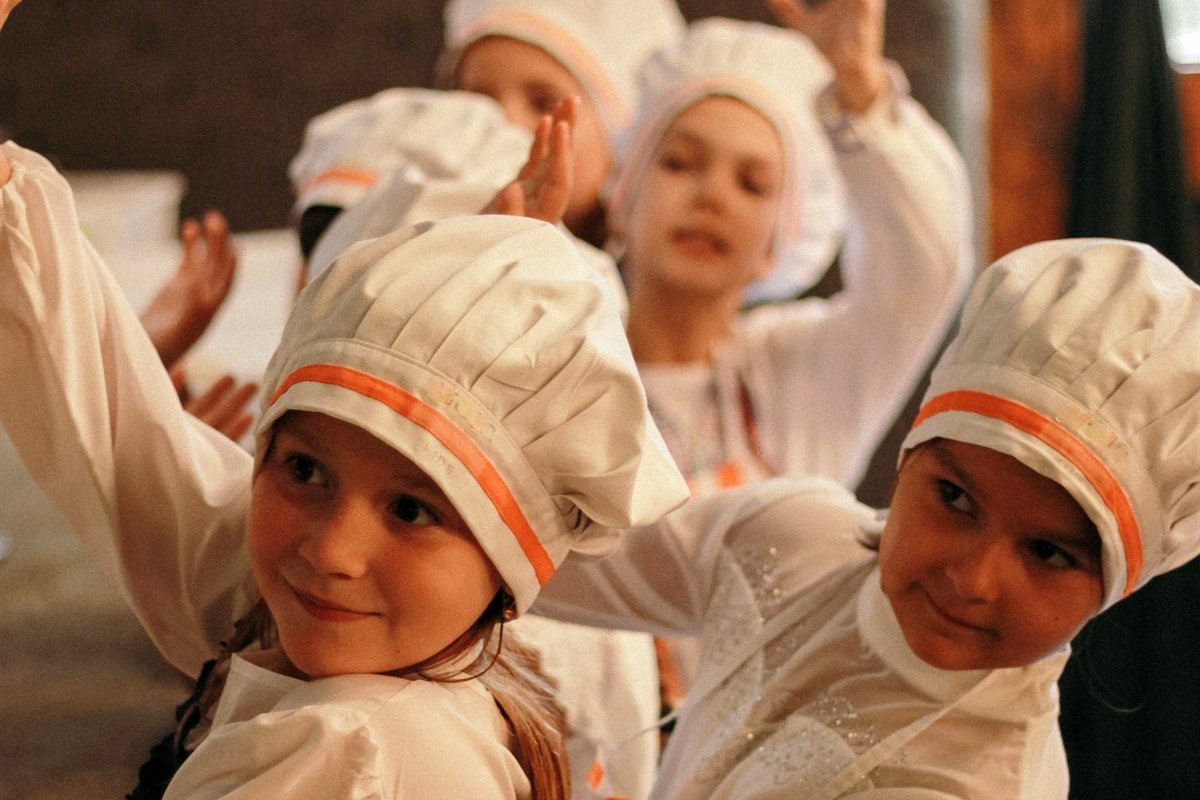Groupe d’enfants en tenue de chef pendant un atelier de cuisine
