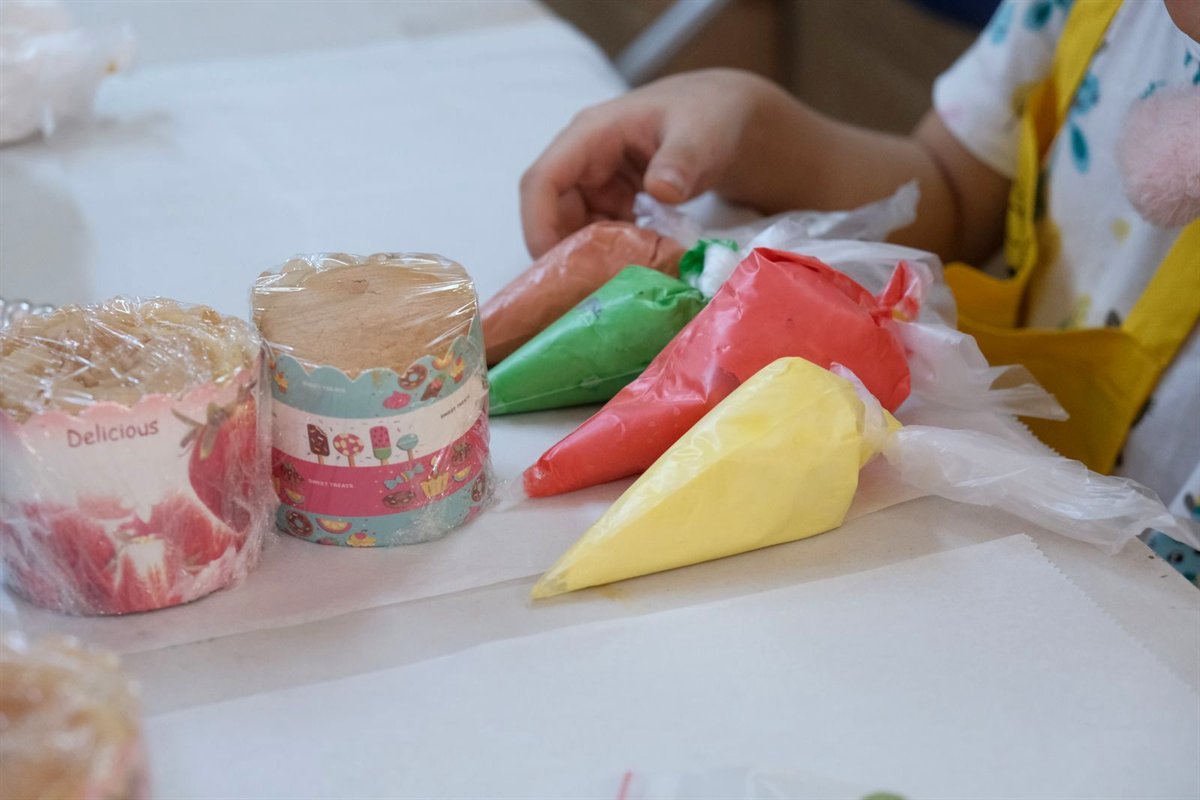 Enfants décorant des cupcakes avec des poches à douille colorées