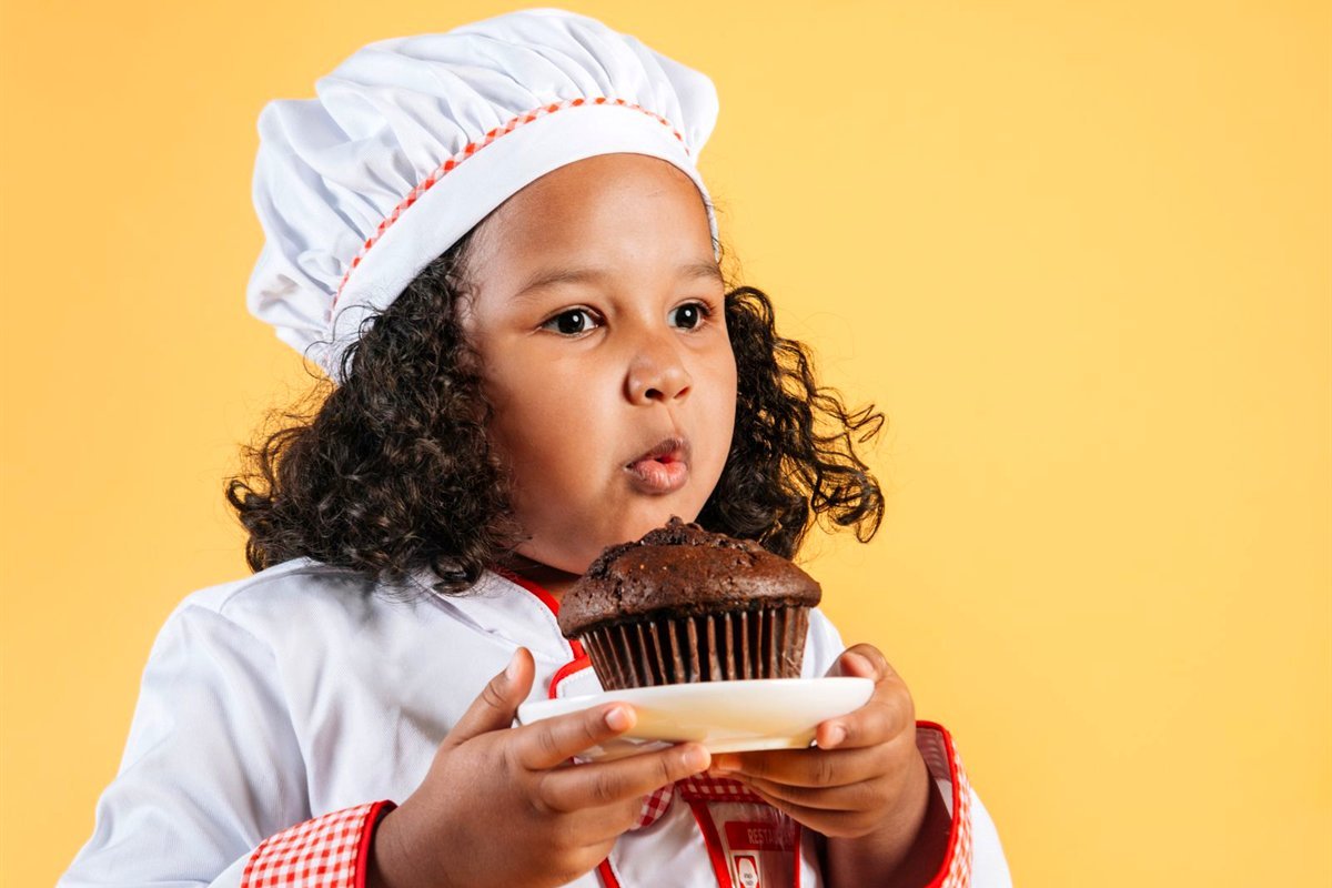 Petite fille en toque soufflant sur un gâteau