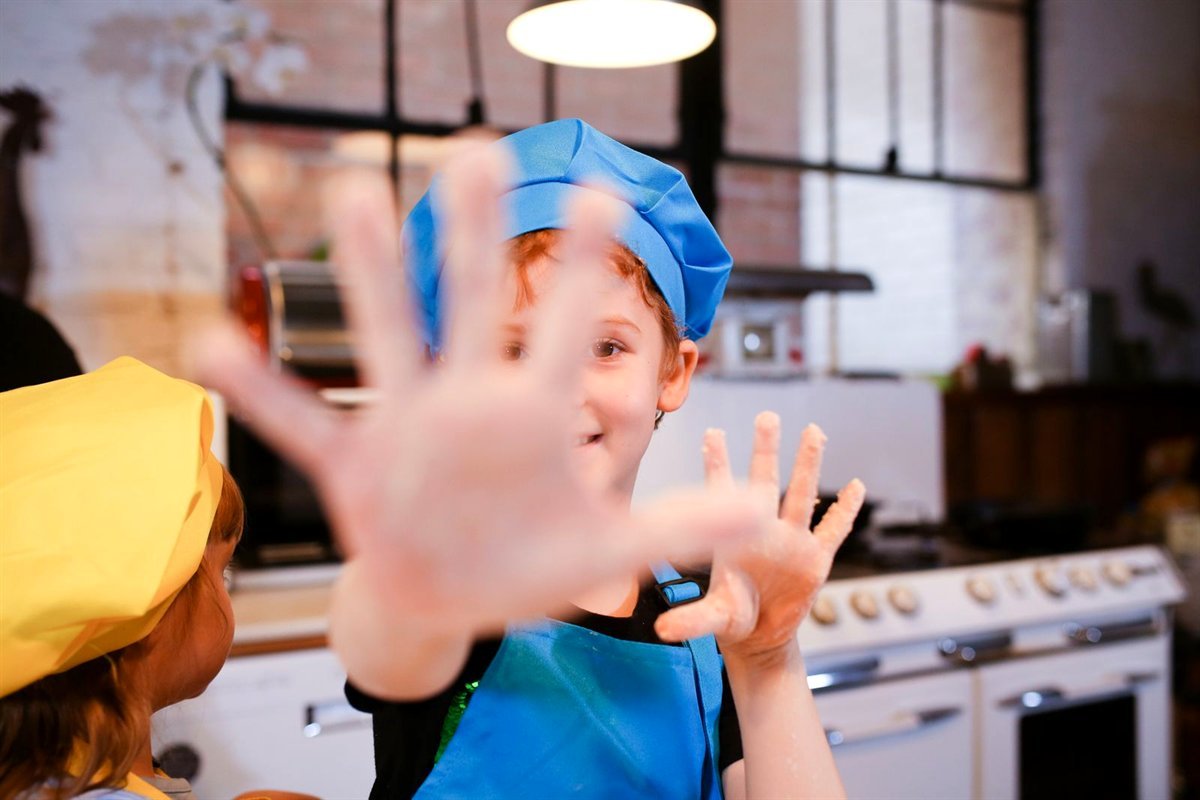 Enfants en toque et tablier pendant un cours de cuisine